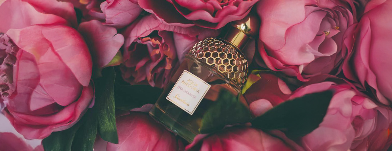 A bottle of spring perfume among pink flowers