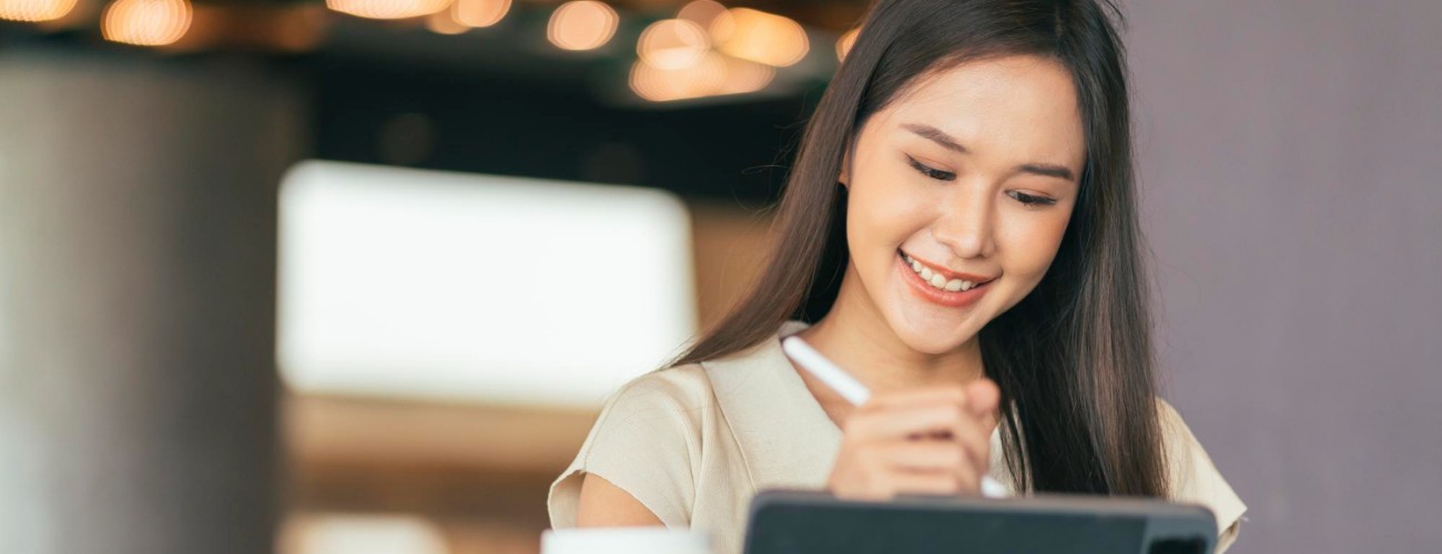 Woman using tablet with stylus at a cafe