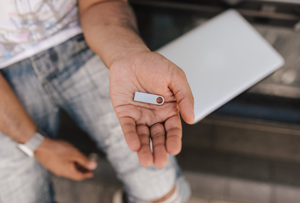 A USB thumbdrive on the palm of a man’s hand.