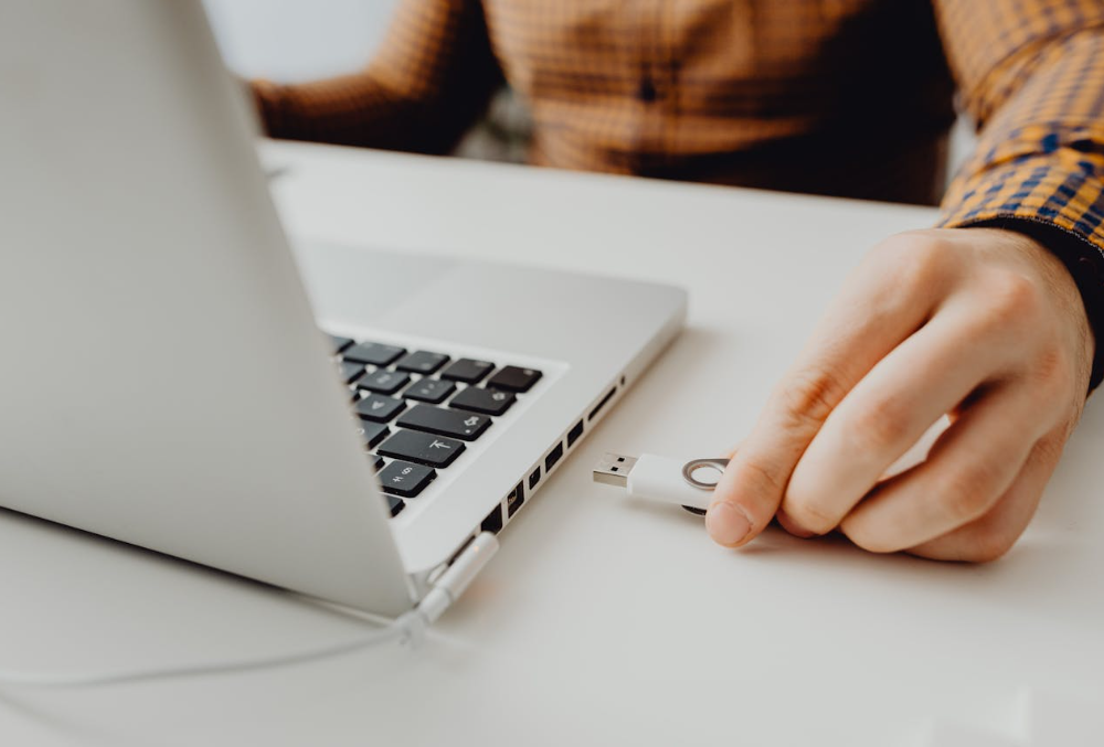 A person plugging a usb flash drive into the laptop.
