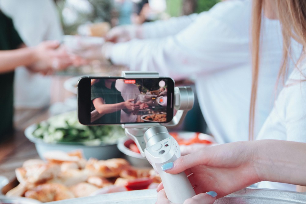 smartphone on a gimbal filming people passing food to each other