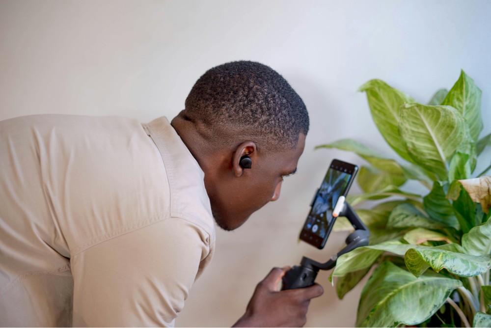 man with a smartphone gimbal filming a plant