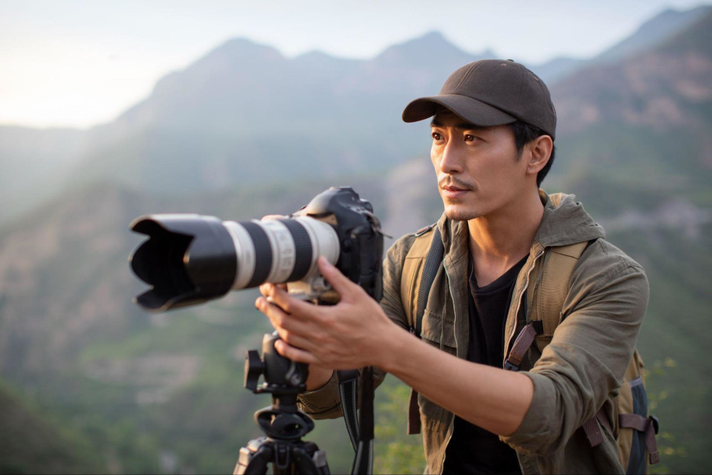 asian man outdoors with a dslr on a tripod