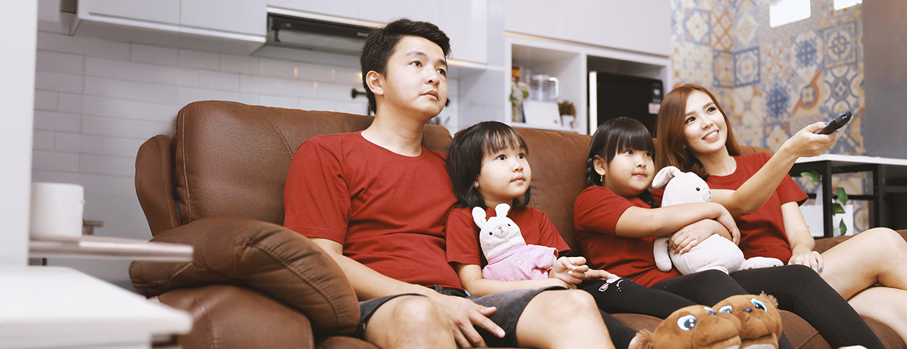 A Singaporean family of four at home watching the National Day Parade on television